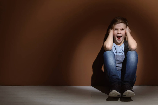 depressiver kleiner Junge, der drinnen auf dem Boden sitzt. Zeit für einen Kinderpsychologen - Foto, Bild