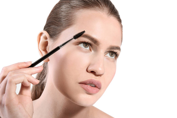 Beautiful woman with perfect eyebrows applying makeup on light background - Φωτογραφία, εικόνα