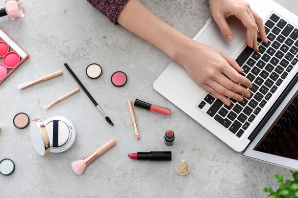 Young woman with makeup products using laptop at table. Beauty blogger - Photo, Image