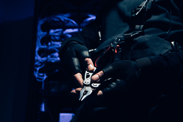 куповані постріл хакер плоскогубцями колючий в руках з кабелі на тлі - Фото, зображення