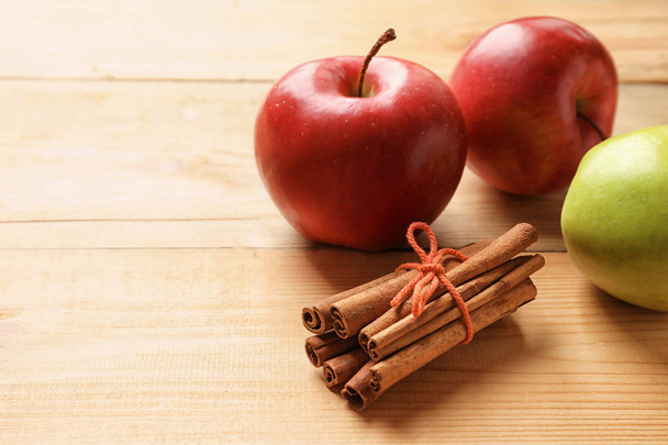 Fresh apples and cinnamon sticks on wooden table - Photo, image