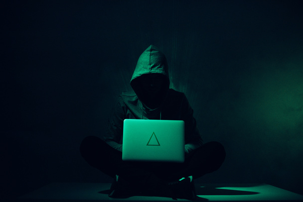 тоновані зображення силует хакер в балахон, використовуючи ноутбук - Фото, зображення