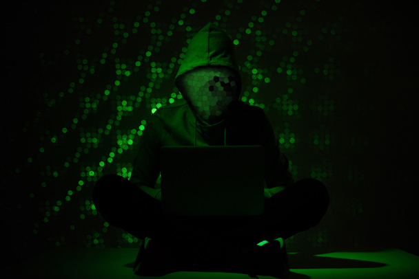 imagen tonificada de la silueta del hacker en sudadera con capucha usando el ordenador portátil
 - Foto, imagen