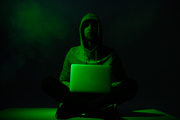 toned picture of hacker in hoodie with laptop - Foto, imagen