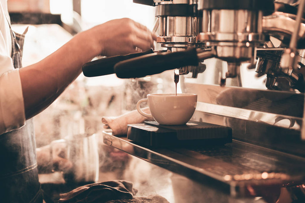 Κοντινό χέρι barista κάνει ένα φλιτζάνι καφέ. - Φωτογραφία, εικόνα