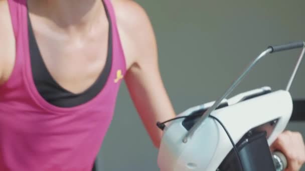 Portrait of young woman riding at stationary bike at the gym in slow motion - Imágenes, Vídeo