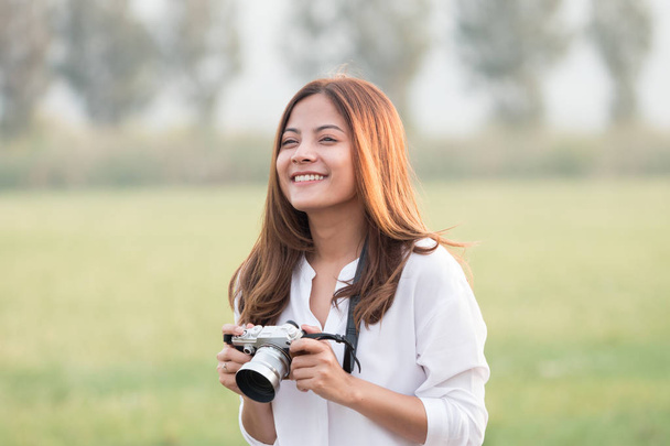 Beautiful Asian woman holding vintage camera in hand and standin - Фото, изображение