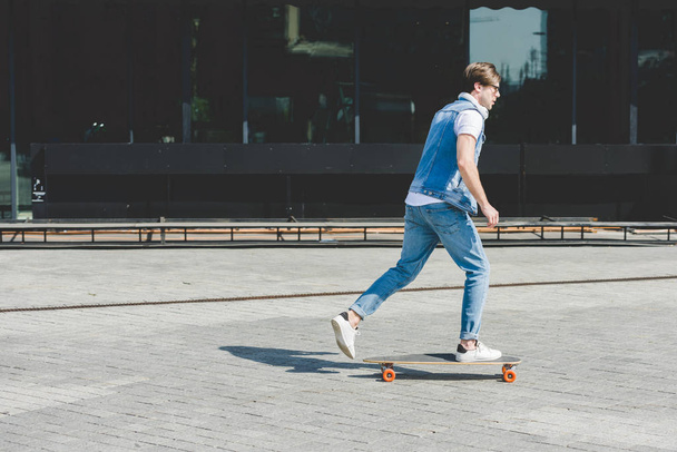 Widok z boku z młodych Skater jazda longboard przez ulicę - Zdjęcie, obraz