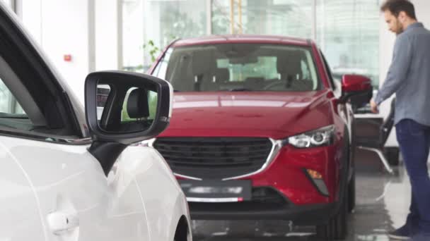 Hombre maduro eligiendo un coche nuevo en el salón de concesionarios
 - Metraje, vídeo