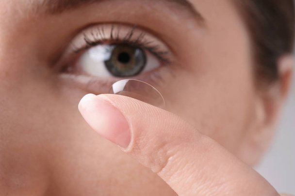 Young woman putting contact lens in her eye, closeup - Foto, afbeelding