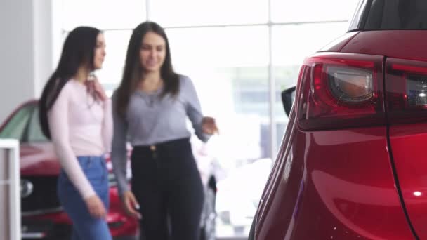 Dwie kobiety, omawiając nowy samochód w salonie dealera - Materiał filmowy, wideo