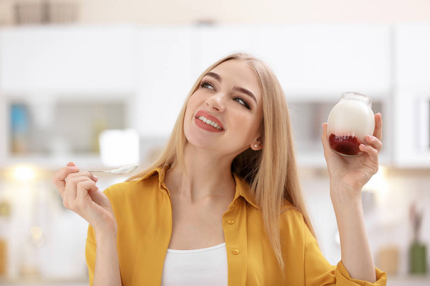 Young woman with yogurt on blurred background - Фото, изображение