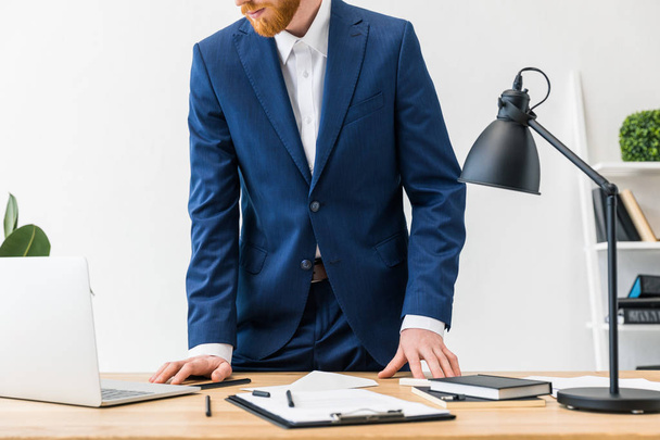 vue partielle de l'homme d'affaires sur le lieu de travail avec ordinateur portable, ordinateurs portables et bloc-notes dans le bureau
 - Photo, image