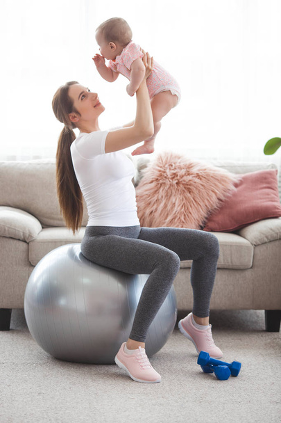 Joven bonita madre haciendo ejercicio con su pequeño hijo en casa
 - Foto, Imagen