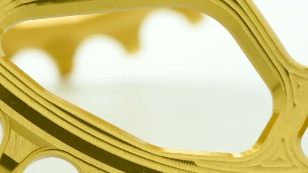 Corrente de bicicleta oval dourada engrenagem girando em fundo branco, forte close-up com detalhes visíveis da estrutura
 - Filmagem, Vídeo