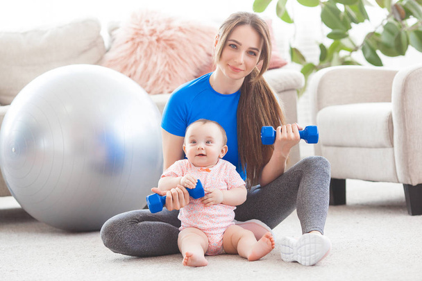 Young pretty mother working out with her little child at home - Photo, Image