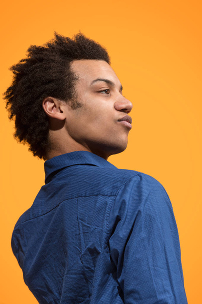 Beautiful male half-length portrait isolated on orange studio backgroud. The young emotional surprised man - 写真・画像