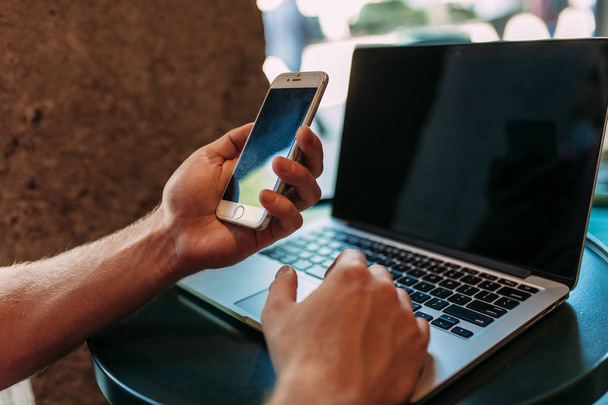 Крупним планом рука, яка тримає телефон, людина в кафе з ноутбуком, технологія
 - Фото, зображення