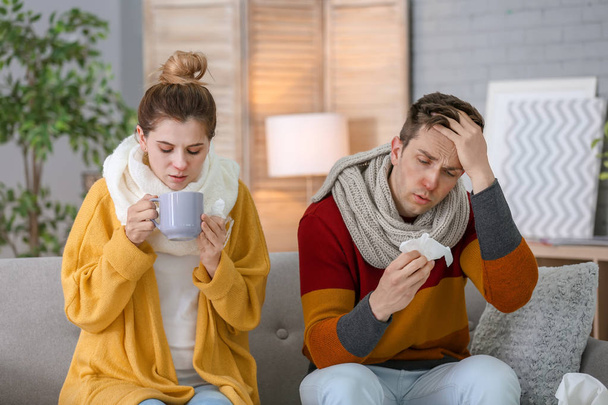 Couple suffering from cold together on sofa at home - Foto, Imagem