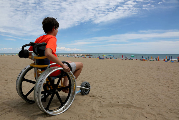 Junge blickt vom Rollstuhl auf das Meer - Foto, Bild