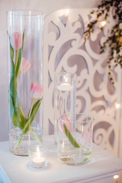 крупним планом фото красивого весільного прикраси з рожевими квітами тюльпанів і білими свічками
  - Фото, зображення