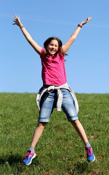 小さな女の子が芝生の上にジャンプします。 - 写真・画像