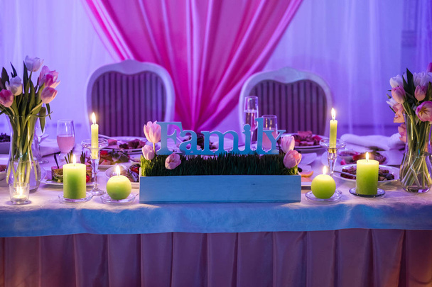 крупным планом фотография красивого свадебного декора с тюльпанами и свечами на фиолетовом столе
 - Фото, изображение