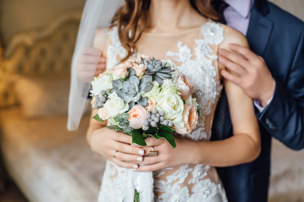 Close-up foto van jong stijlvolle koppel houden van bloemen boeket op de huwelijksdag - Foto, afbeelding
