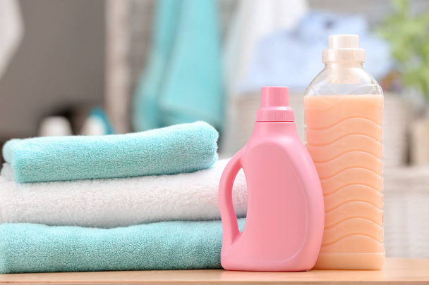 Stack of clean towels and bottles with detergent on table - Foto, imagen