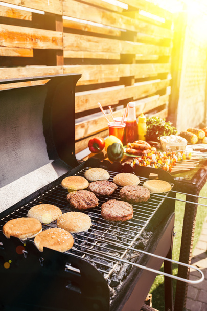 Dinner with vegetables and burgers grilled for outdoors barbecue - 写真・画像