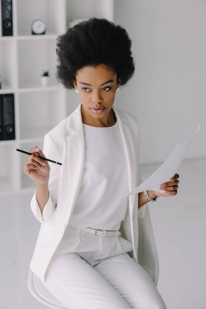 attractive african american businesswoman holding document and pencil in office - Фото, зображення