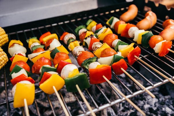 Summer vegetables with mushrooms on skewers and sausages grilled for outdoors barbecue - Fotó, kép