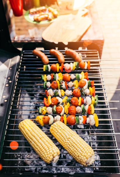 Summer vegetables with mushrooms on skewers and sausages cooked outdoors on grill - Foto, afbeelding