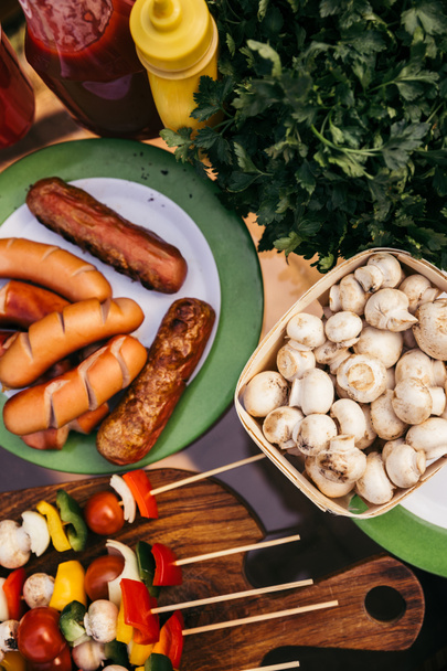 Горячие вкусные сосиски и овощи с грибами, приготовленные на открытом воздухе
 - Фото, изображение