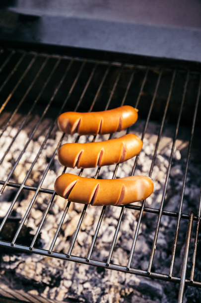Salsichas quentes cozidas ao ar livre na grelha sobre carvão
 - Foto, Imagem