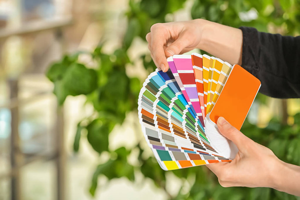Женщина-дизайнер держит образцы цветовой палитры на размытом фоне
 - Фото, изображение