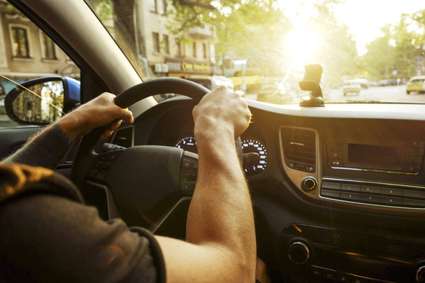 Yumuşak günbatımı ışık direksiyonuna oturan erkek Şoförlü araba iç. Lüks araç kontrol paneli ve elektronik. - Fotoğraf, Görsel