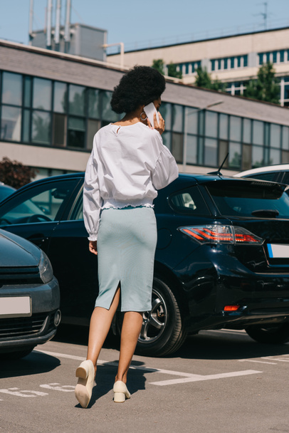africká americká podnikatelka mluví o smartphone na parkování pohled zezadu - Fotografie, Obrázek