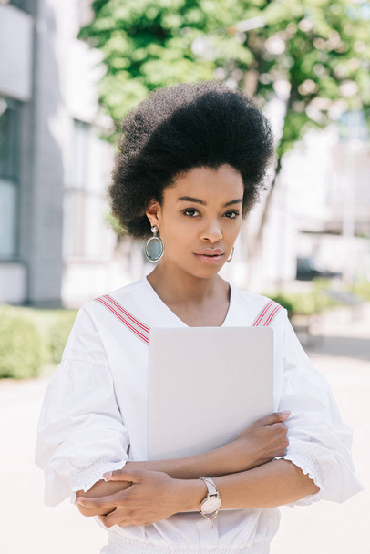 attractive african american businesswoman standing on street with laptop - Photo, Image