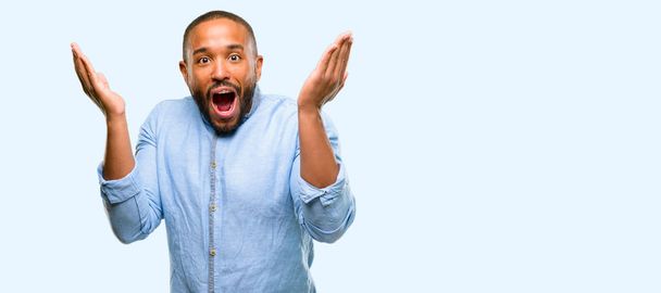 Mutlu ve ifade wow jest tezahürat sakallı Afrikalı-Amerikalı adam üzerinde mavi arka plan izole - Fotoğraf, Görsel