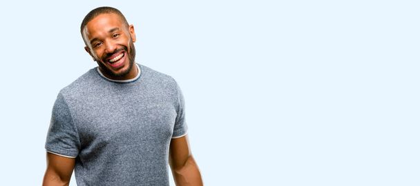 Африканский американец с бородой уверенный и счастливый с большой естественной улыбкой смеется, естественное выражение лица изолированы на синем фоне
 - Фото, изображение