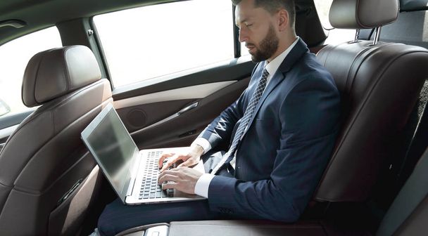 Бизнесмен, использующий ноутбук на заднем сидении автомобиля
 - Фото, изображение