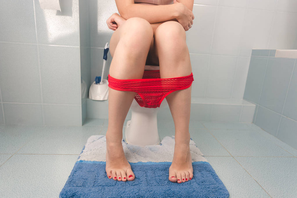 Closeup image of female legs sitting on toilet - Φωτογραφία, εικόνα