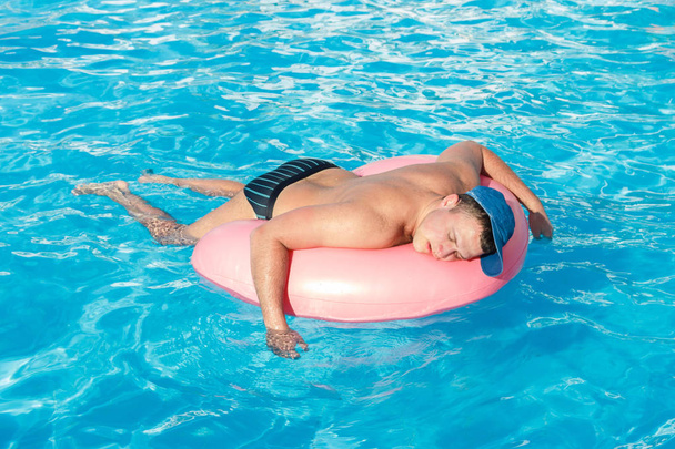 drunk resting guy on the inflatable circle in the swimming pool of the hotel - Photo, Image