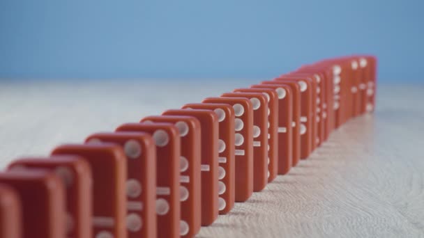 Domino effect - a series of red dominoes falling down the chain on blue background - Footage, Video