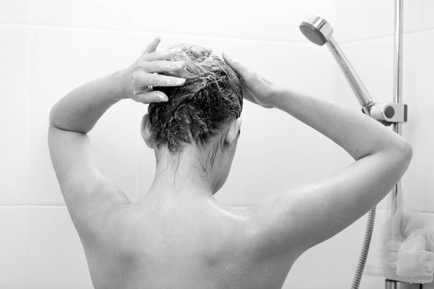 Крупним планом чорно-біле фото молодої брюнетки миття волосся з шампунем
 - Фото, зображення
