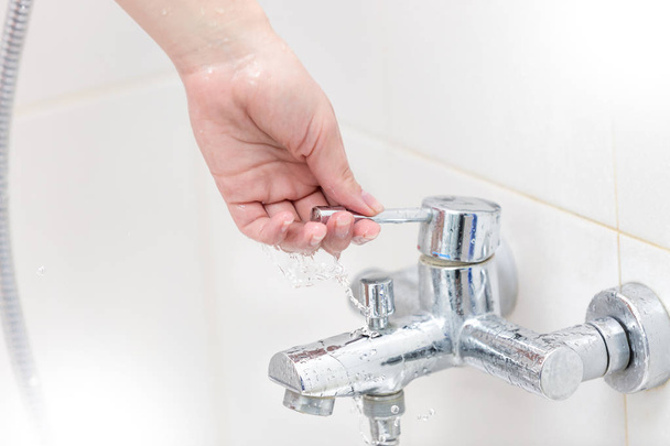 Closeup image of female hands opens water tap in bathroom - Photo, Image
