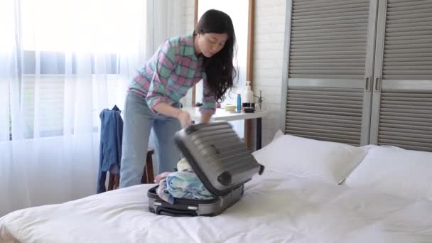 Quick motion of the woman pulling everything out the suitcase and threw them all over around. - Video, Çekim