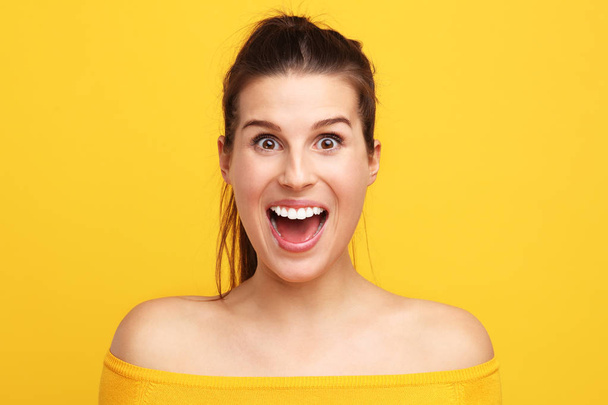 Picture of woman making faces against yellow background - Foto, afbeelding