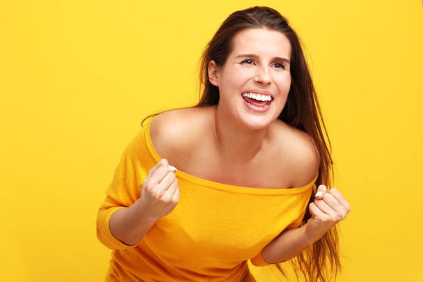 Picture of woman making faces against yellow background - Foto, imagen